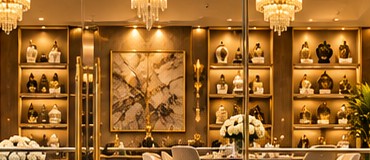 Backlit shelving of black and ivory vases around a framed abstract artwork